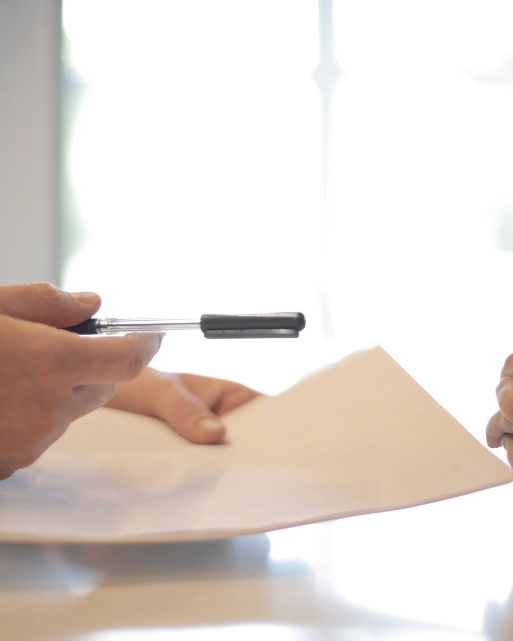 Two people at a table reviewing a printed document together in daylight.